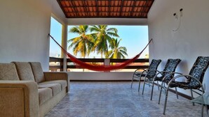 A room with a hammock, a sofa, and chairs, with a view of palm trees through large windows. - Pousada Solar da Lagoa Baixio (Esplanada)