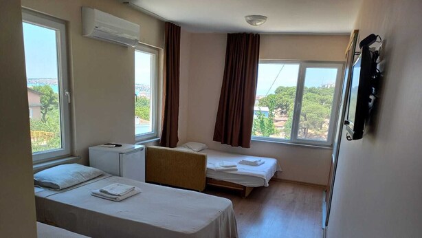 Habitación de hotel con dos camas, un escritorio pequeño, aire acondicionado y ventanas amplias que dan a vistas del exterior.