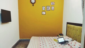 Ein Zimmer mit einem Bett, einem Laptop und einer Wanduhr.
