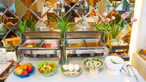 A buffet with various food items and a mirror reflecting the room.