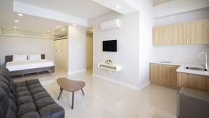 A modern apartment with a bedroom, living area, and kitchen.