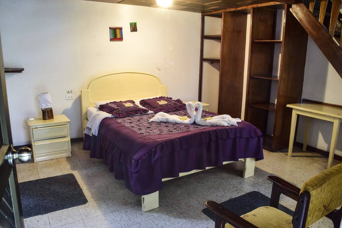 A bedroom with a bed, bedside tables, a chair, a wooden ladder, and a small table.