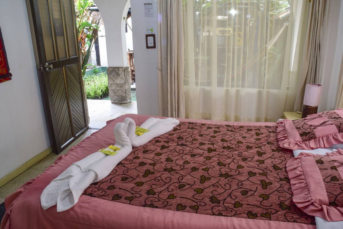 A hotel room with a bed, a door, and a window with curtains.