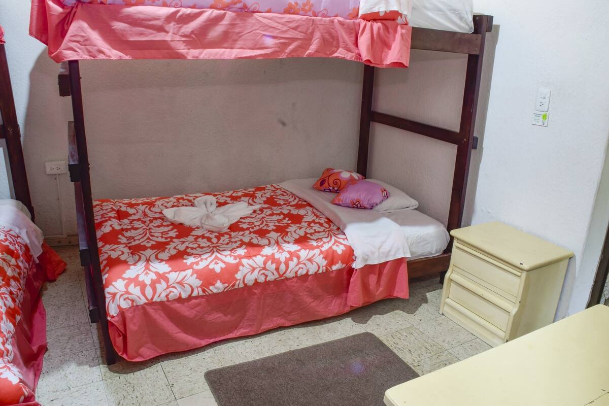 A bunk bed with a floral bedspread, a bedside table, and a small dresser.