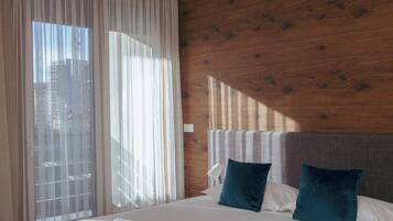 Quarto de hotel com cama, cortinas, parede de madeira e janela.