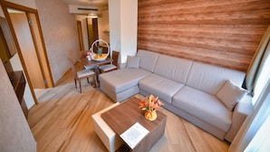 A modern living room with a sectional sofa, a wooden coffee table, and a dining area with a table and chairs. - Central Inn (Zlatibor)