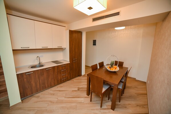 Cocina moderna con armarios de madera, un lavamanos y un comedor con mesa y sillas de madera.
