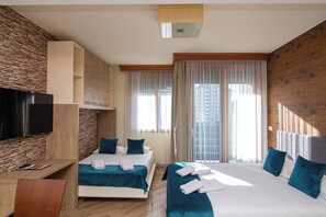 Hotellihuone, jossa on sänky, työpöytä, televisio ja näkymä kaupunkiin.