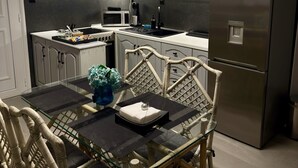 Eine moderne Küche mit grauen Schränken, einem Edelstahlkühlschrank, einem Esstisch mit Stühlen und einer Mikrowelle.