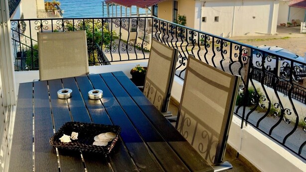 Ein Balkon mit Tisch, Stühlen und Blick aufs Meer.