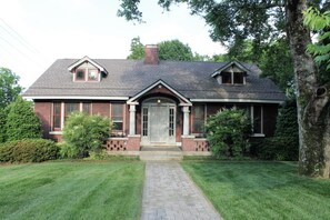 A two-story brick house with a central entrance, a small porch, and a chimney.