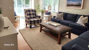 A living room with a checkered armchair, a dark blue sofa, and a wooden coffee table. - Nautical Comfort near Rail Trail (Chatham)