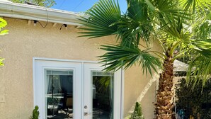 Una casa con puerta corrediza de vidrio, una palmera y dos plantas en macetas.