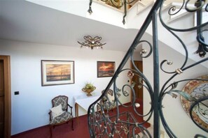 A staircase with ornate metal railings, a chandelier, and framed artwork on the walls.