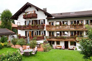 Un immeuble de deux étages doté de balcons, d’un jardin et d’un espace extérieur aménagé pour s’asseoir.