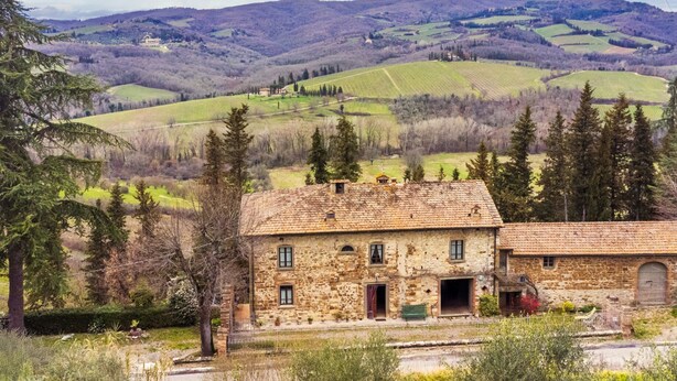 A stone building with a rustic appearance, surrounded by lush greenery and a hilly landscape in the background. - La Terrazza by Interhome (Radda in Chianti)