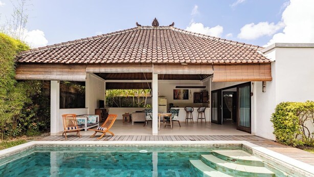 A house with a tiled roof, a swimming pool, and a covered outdoor seating area.