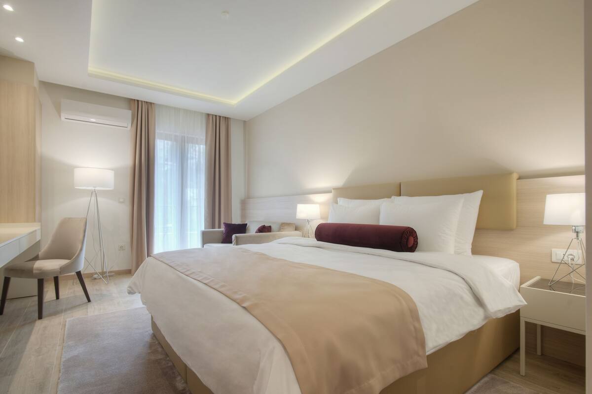 A modern hotel room with a large bed, a desk, and a chair.