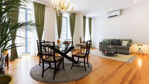 A spacious living area with a dining table, chairs, a sofa, and a chandelier.