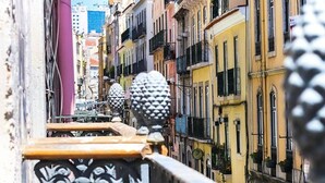 A narrow street with colorful buildings, a metal railing, and a clear view of the street.