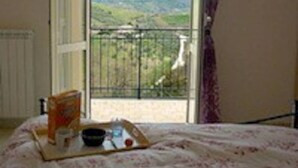 A bedroom with a bed, a window with a view of a landscape, and a tray with a book and a cup on the windowsill. - Casa Maya With Private Pool (Serramonacesca)
