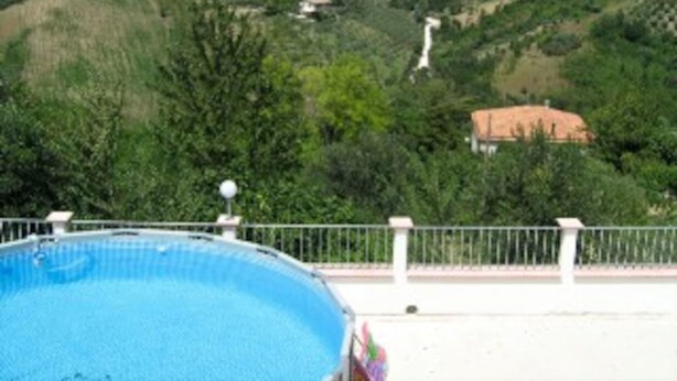 A swimming pool with a view of a hilly landscape and a distant building. - Casa Maya With Private Pool (Serramonacesca)