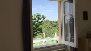 A room with a window overlooking a green landscape and a building on a hill. - Casa Maya With Private Pool (Serramonacesca)
