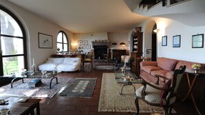 A spacious living room with a fireplace, a white sofa, a red sofa, and a dining area with a table and chairs. - Il Casale, elegant villa with stunning sea views (Formia)