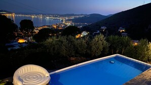 An infinity pool with a view of a cityscape at dusk. - Il Casale, elegant villa with stunning sea views (Formia)