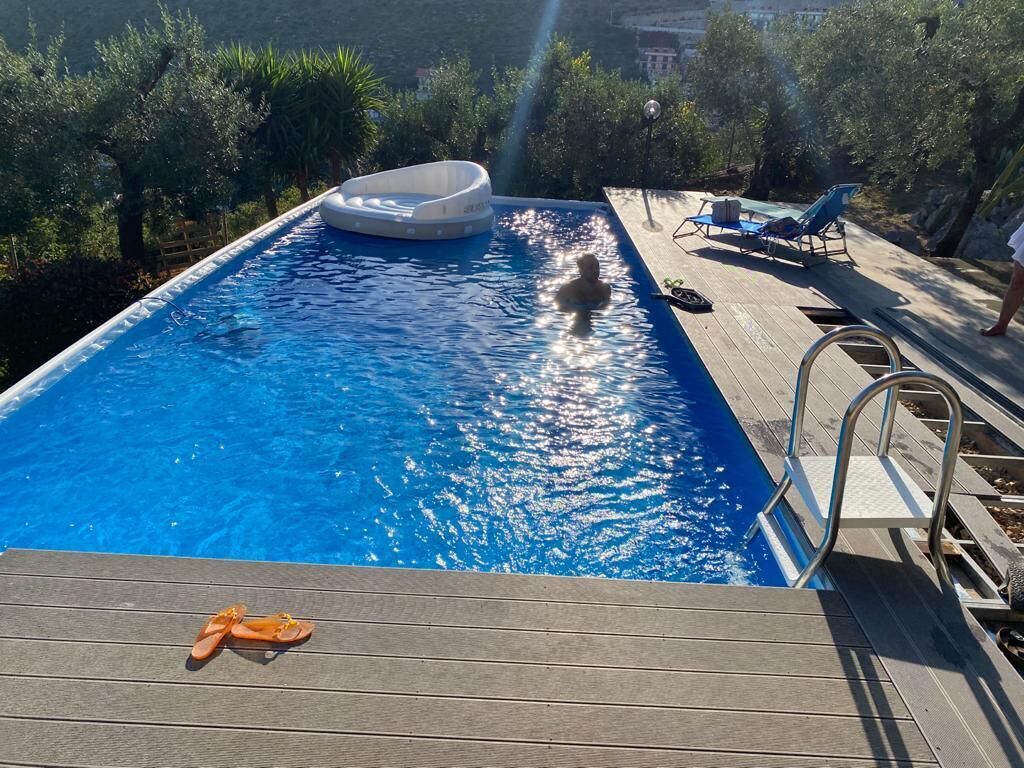 Ein Schwimmbecken mit Holzterrasse, Liegestühlen und einem Whirlpool.