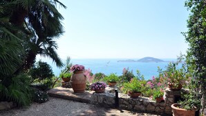A paved pathway leading to a stone wall with large terracotta pots containing pink flowers. - Il Casale, elegant villa with stunning sea views (Formia)