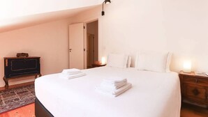 Un dormitori amb un llit gran, una commode, una tauleta de nit i una làmpada.