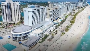 Un hôtel situé sur la côte, composé de plusieurs immeubles de grande hauteur, et doté d’une plage et d’un espace piscine.