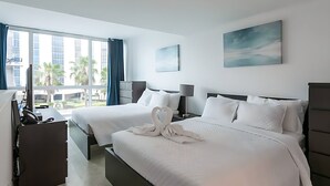 Une chambre d’hôtel avec deux lits, un bureau et une grande fenêtre avec des rideaux.