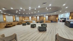 Un hall d’hôtel spacieux avec un espace salon central, un comptoir d’accueil et une cuisine en arrière-plan.