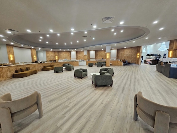 A spacious hotel lobby with a central seating area, a reception desk, and a kitchen in the background. - BEACHFRONT ONE BEDROOM 2 BATH CONDO-HOTEL WITH PARKING ON THE BEACH (Miami)