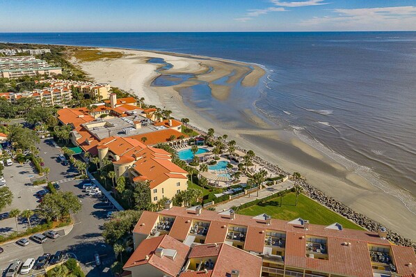Ein Hotel an der Küste mit mehreren Gebäuden, einem Schwimmbad und einem Strand.