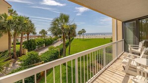 A balcony with a view of a beach, palm trees, and a grassy area. - Enjoy Full Resort Access and Ocean Views at KP247! (Saint Simons Island)