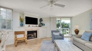 A living room with a fireplace, a television, a sofa, and a coffee table. - Enjoy Full Resort Access and Ocean Views at KP247! (Saint Simons Island)