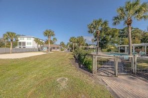A residential area with a swimming pool, palm trees, and a wooden deck.