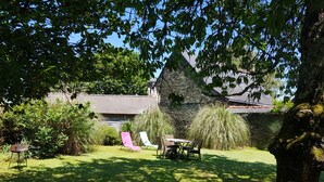 Ein Garten mit Steinmauer, Tisch und Stühlen.
