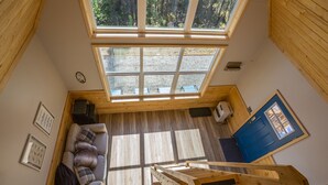 Una habitación con techos altos, tragaluces, una puerta azul y una escalera de madera.