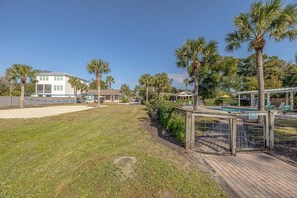 A residential area with a swimming pool, palm trees, and a wooden deck.