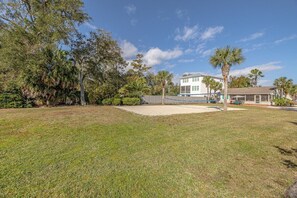 A residential property with a large lawn, a swimming pool, and a house with a white exterior.