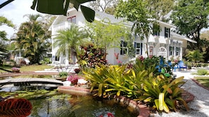 A white house with a garden, a pond, and a bicycle. - Beautiful luxury 2 bedroom private   Cottage (Dunedin)