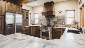Una cucina con mobili in legno, un frigorifero in acciaio inox, un piano cottura e una grande isola con lavello.