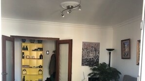 Huoneessa on keltainen hyllykkö, kattotuuletin, juliste, lamppu ja ruukussa oleva kasvi.