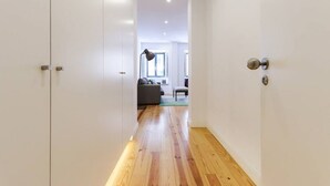 Un couloir avec un plancher en bois, des murs blancs et une porte sur le côté droit.