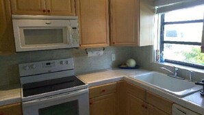 Una cocina con armarios de madera, microondas, horno y lavabo.