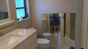 Un baño con lavamanos, espejo y dos inodoros.